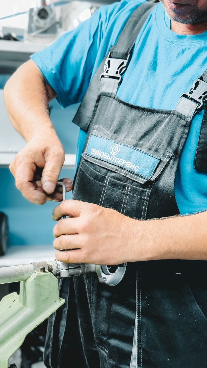 Mastering the First Impression: Your intriguing post title goes here Close-up of a plumber in blue uniform working on a pipe repair with a wrench.