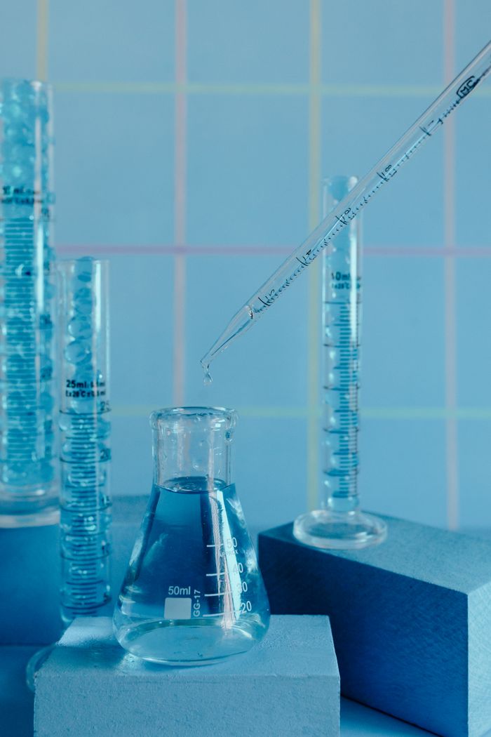 services-04 Collection of blue-toned glassware in a laboratory setting with pipette and graduated cylinders.